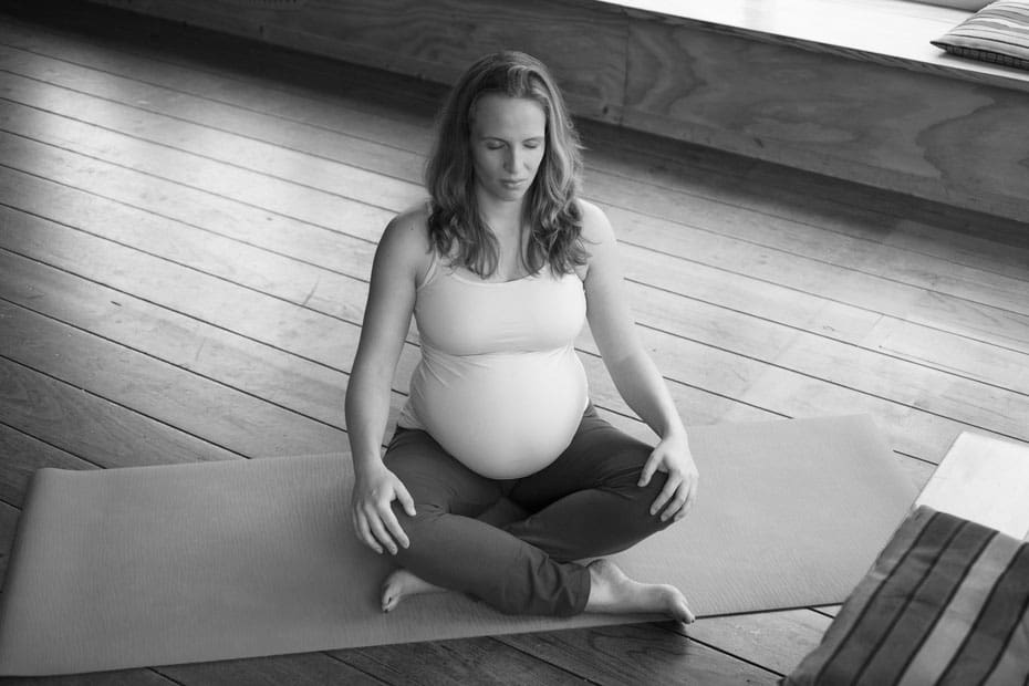 Zwangerschaps yogapose. Yogadocente Robin op yogamat in kleermakerszit.